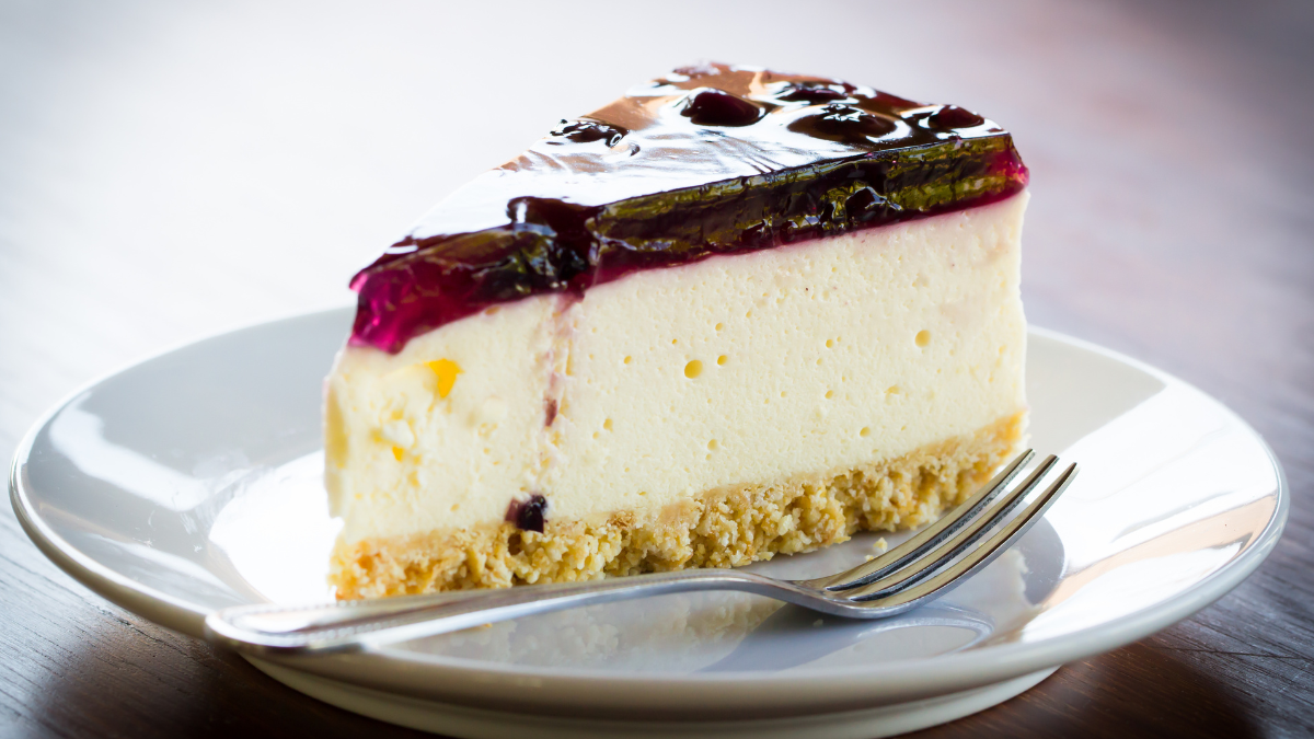 Cheesecake slice made with sour cream as a substitute for cream cheese on a white plate.