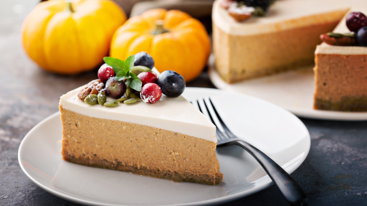 A creamy cheesecake with sour cream topping on a wooden table, topped with fresh berries.