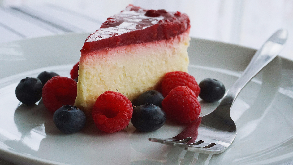 A rich and creamy cheesecake topped with sour cream and garnished with fresh fruit.