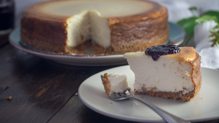 Cheesecake slice with a creamy texture, served with a dollop of sour cream on a plate.