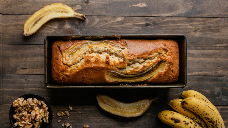 A freshly baked loaf of banana bread with slices, showcasing its moist texture and golden crust.