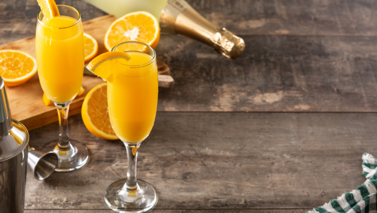 A glass of mimosa with sparkling wine and fresh orange juice served at a brunch table.