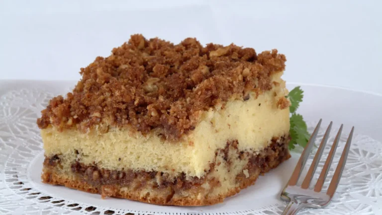 A freshly baked banana crumb cake with a golden crumb topping, served on a white plate.