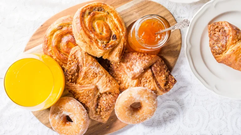 A flaky croissant with fresh fruit and a cup of coffee on a breakfast table.