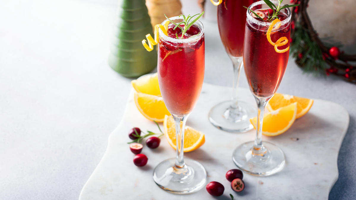 Glass of cranberry mimosa garnished with fresh cranberries and rosemary sprig