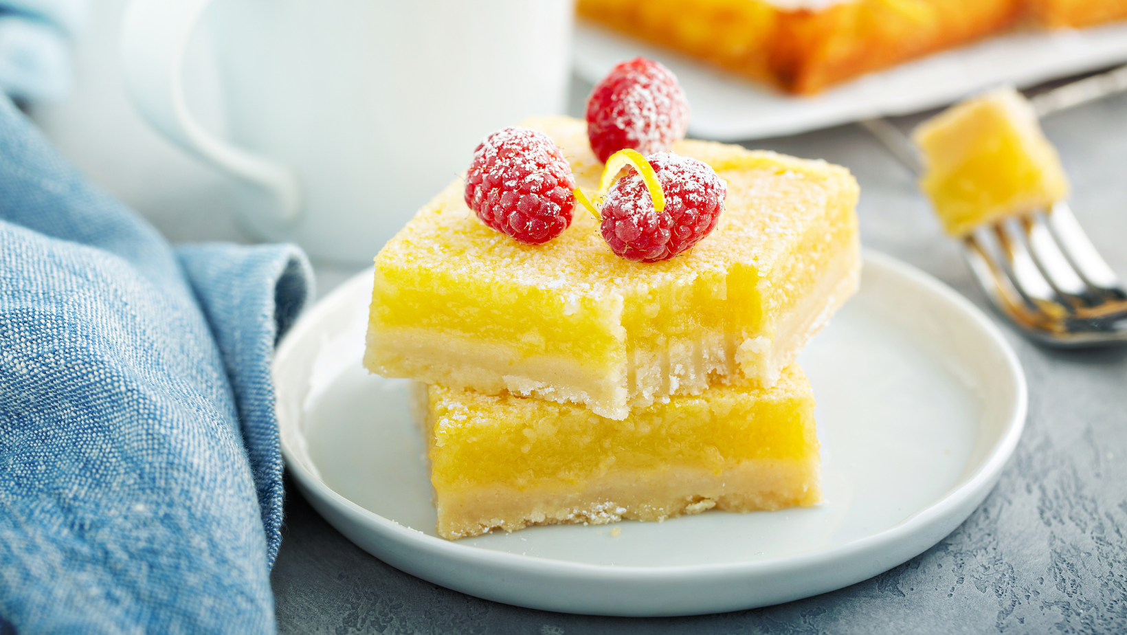 Freshly baked gluten-free lemon bars with a powdered sugar topping, served on a white plate