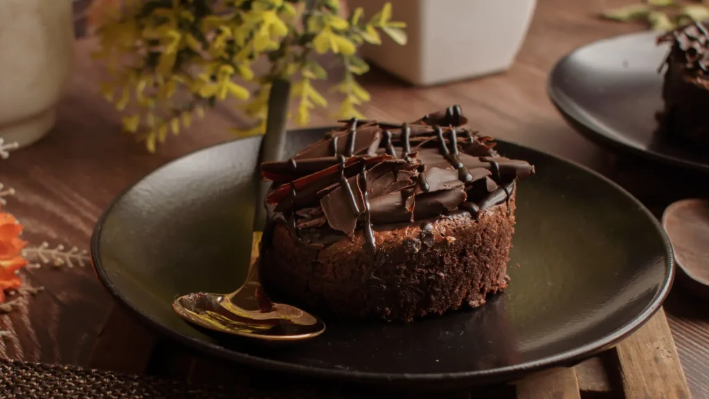 Moist and rich chocolate pound cake topped with powdered sugar on a wooden plate.