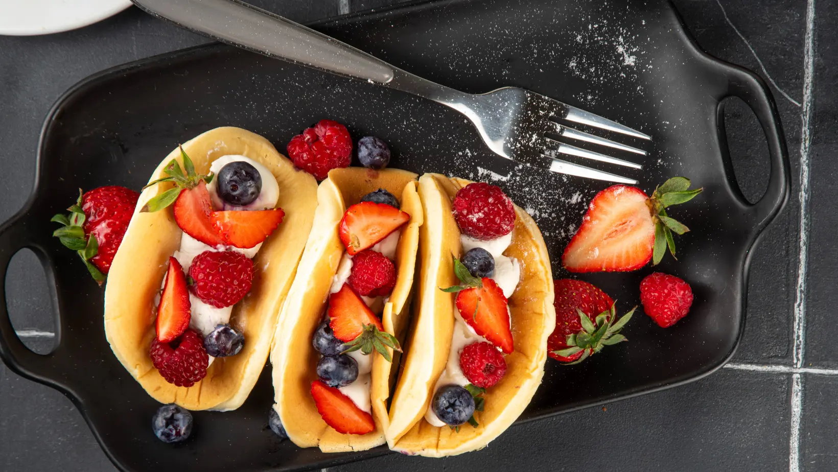 A stack of fluffy pancakes topped with fresh berries and syrup, a perfect example of sweet breakfast recipes.