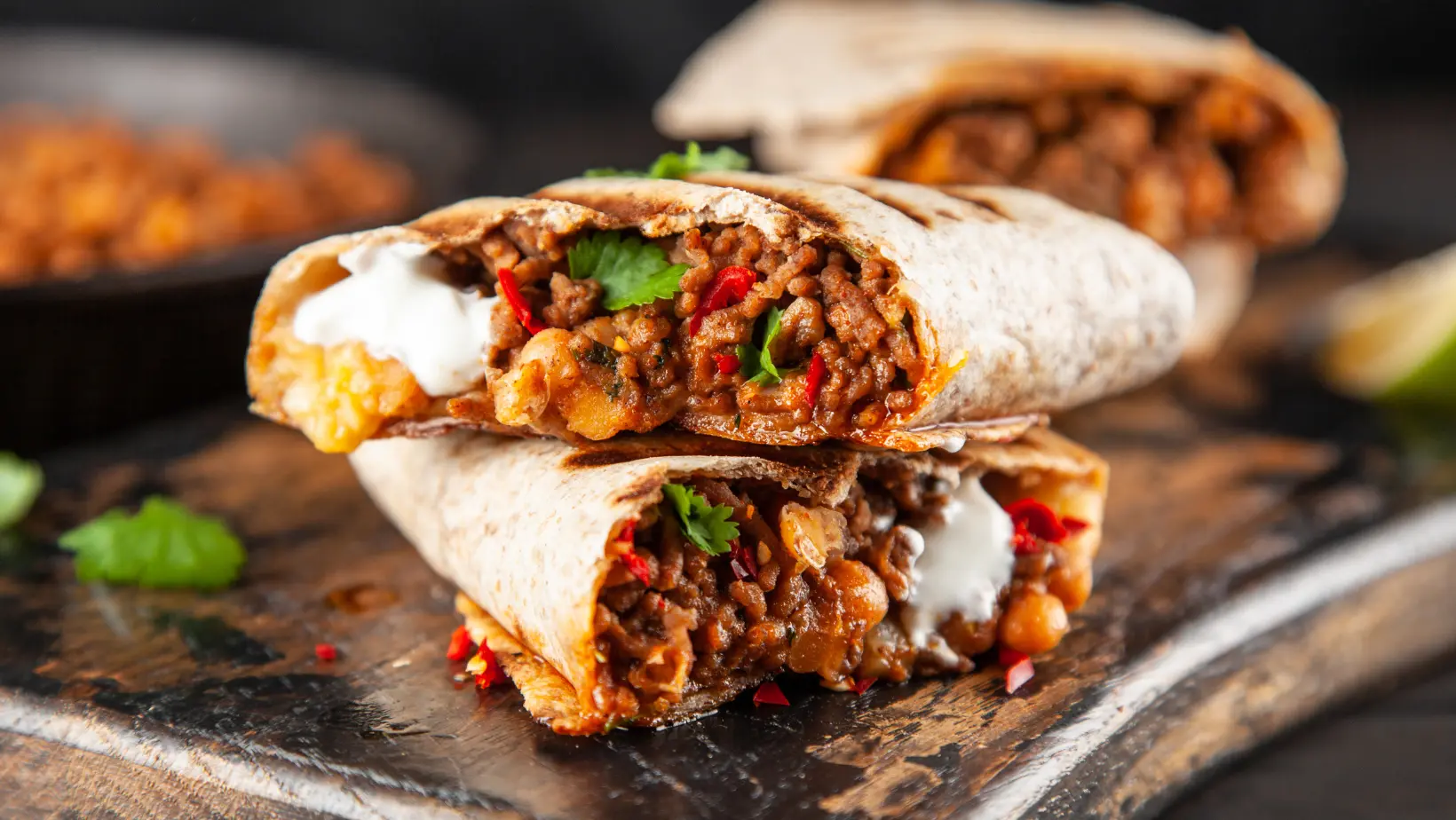 A close-up of a breakfast burrito filled with scrambled eggs, bacon, vegetables, and melted cheese.