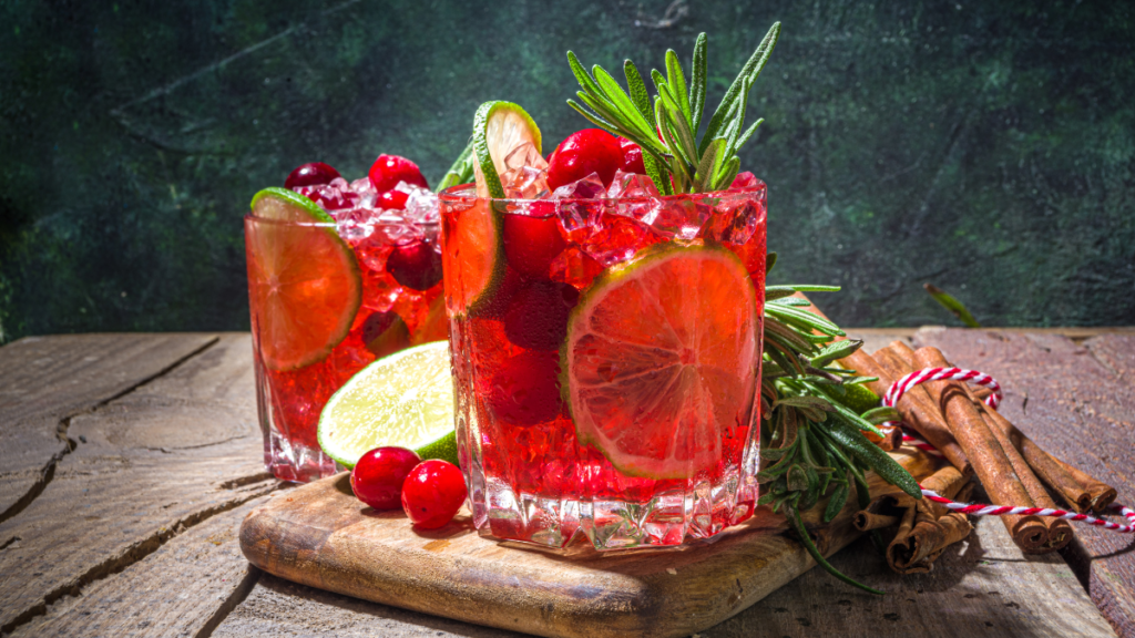 A glass of sparkling Prosecco and cranberry juice cocktail garnished with fresh cranberries and rosemary.