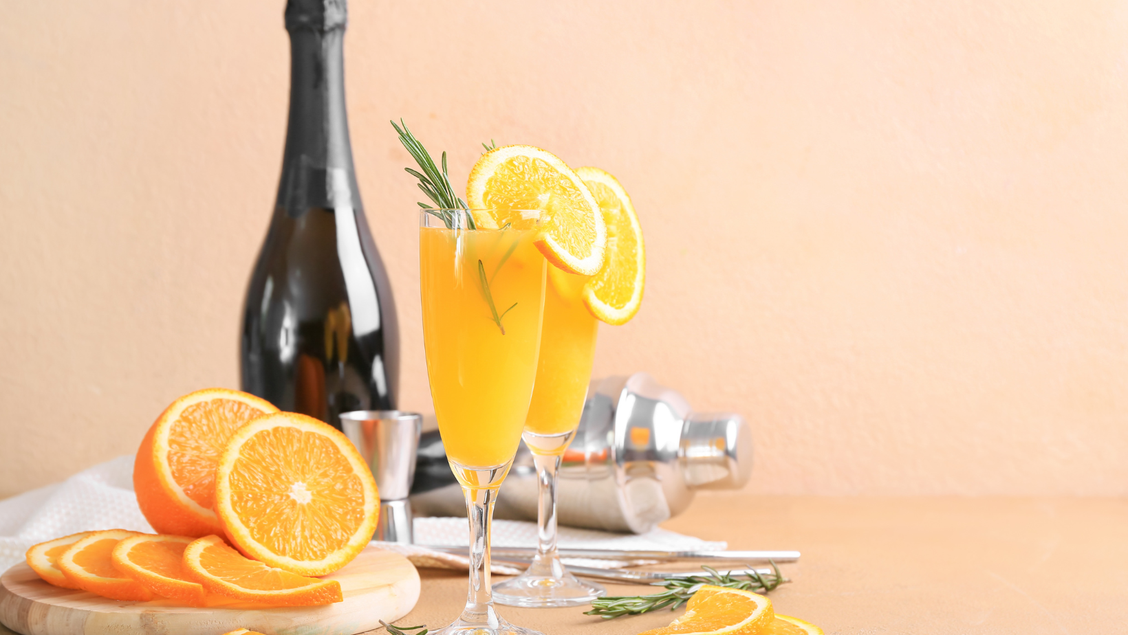 A refreshing mimosa with champagne and orange juice garnished with a slice of orange in a tall flute glass.