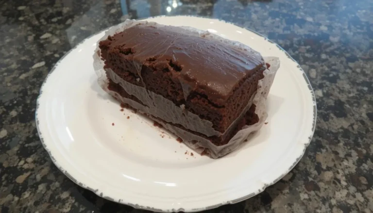 Dry chocolate pound cake sliced on a plate with frosting and fresh berries.